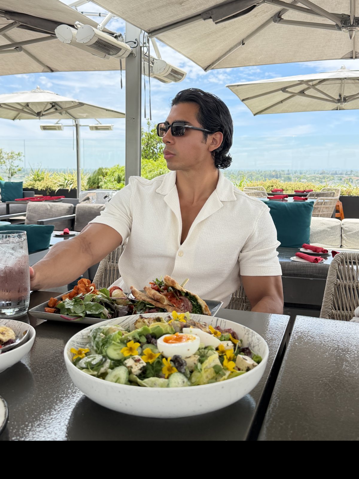 The founder at a rooftop table, mid-conversation, looking away from the camera.